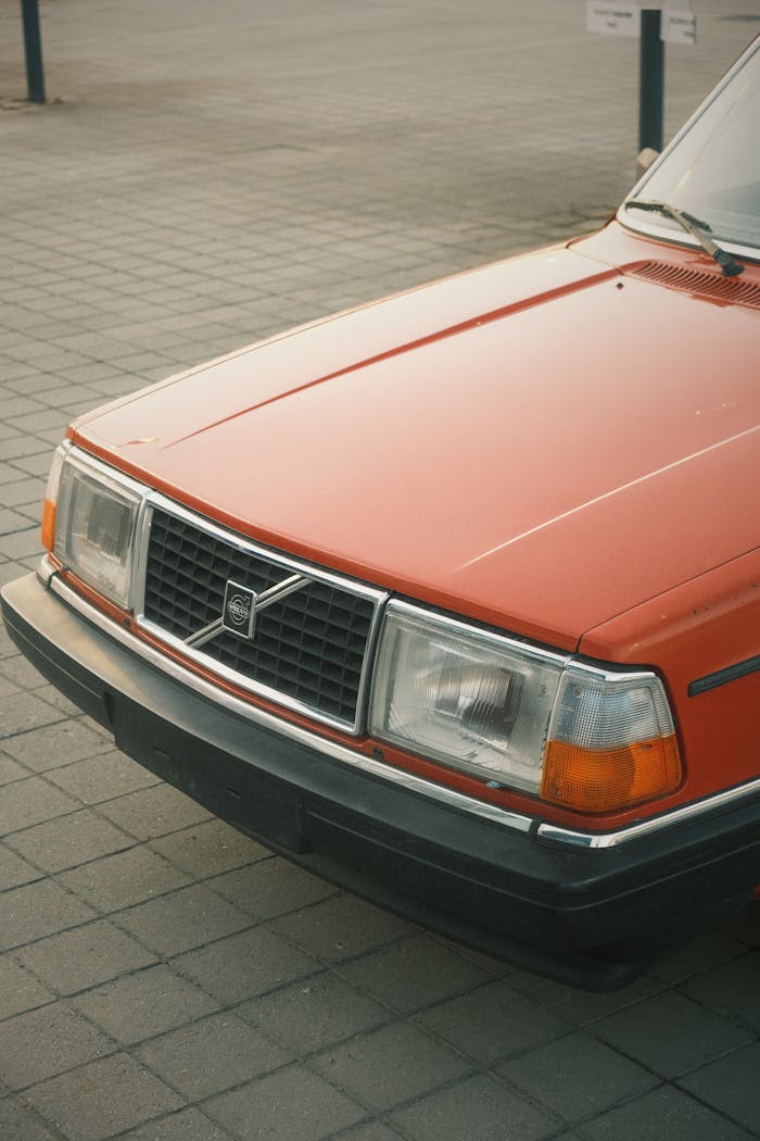 creative Close-up of a classic red Volvo car in an urban environment, showcasing a vintage aesthetic.